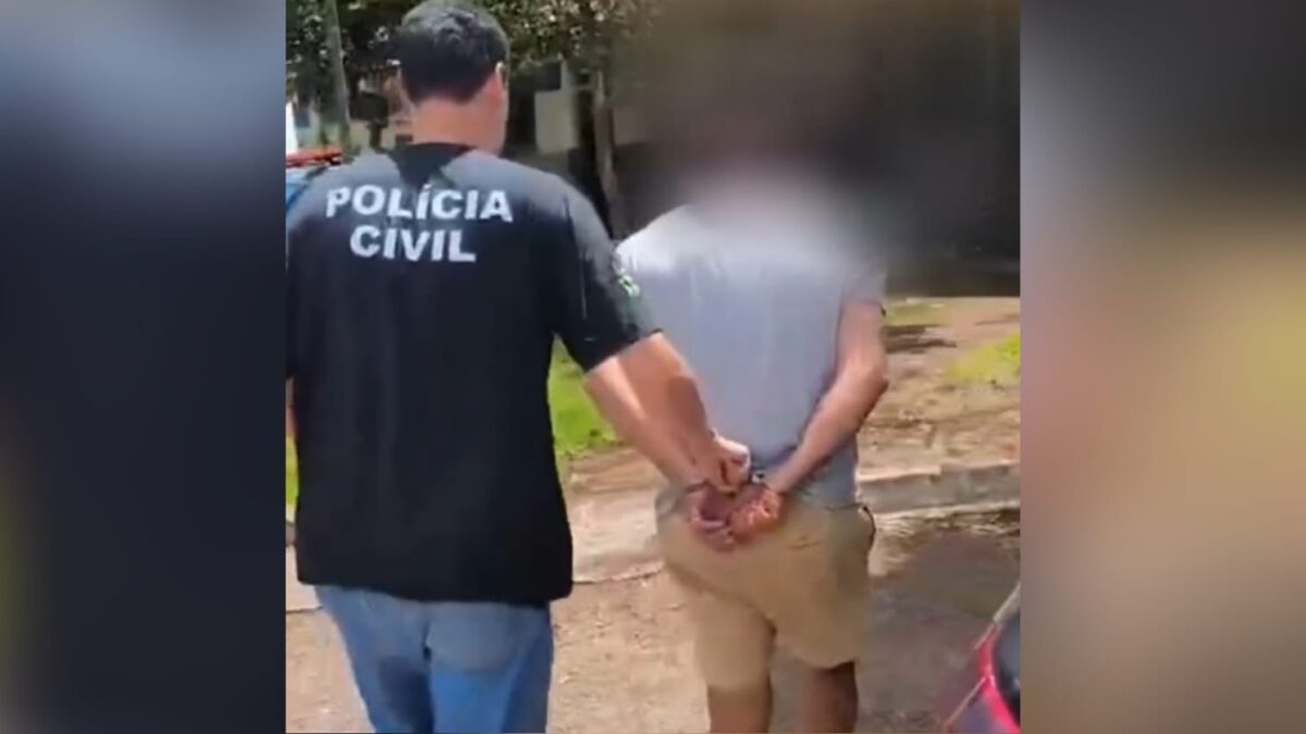 A imagem mostra um homem algemado sendo levado por um policial civil