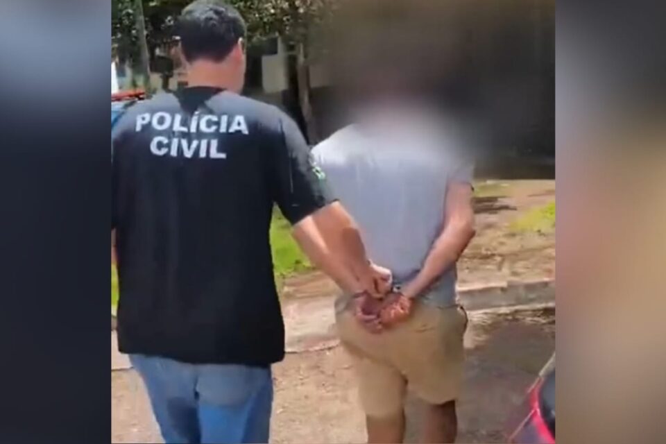 A imagem mostra um homem algemado sendo levado por um policial civil