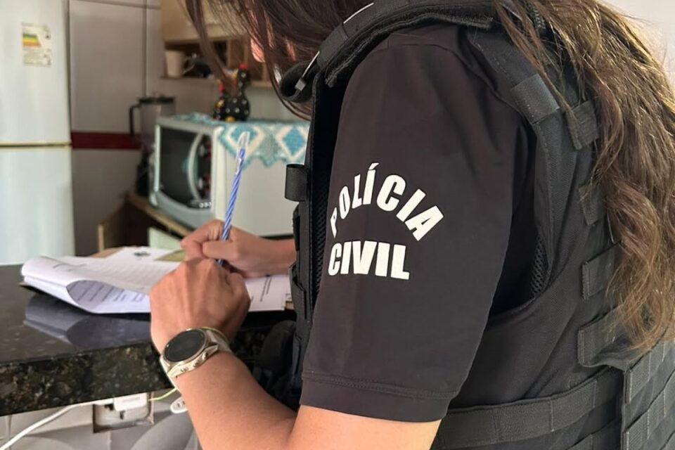 A imagem mostra uma policial preenchendo papéis de atuação no local