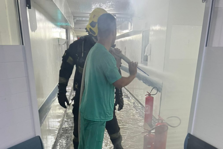 Imagem colorida mostra um médico e um bombeiro militar durante o combate a um incêndio que atingiu o Hospital Estadual de Aparecida
