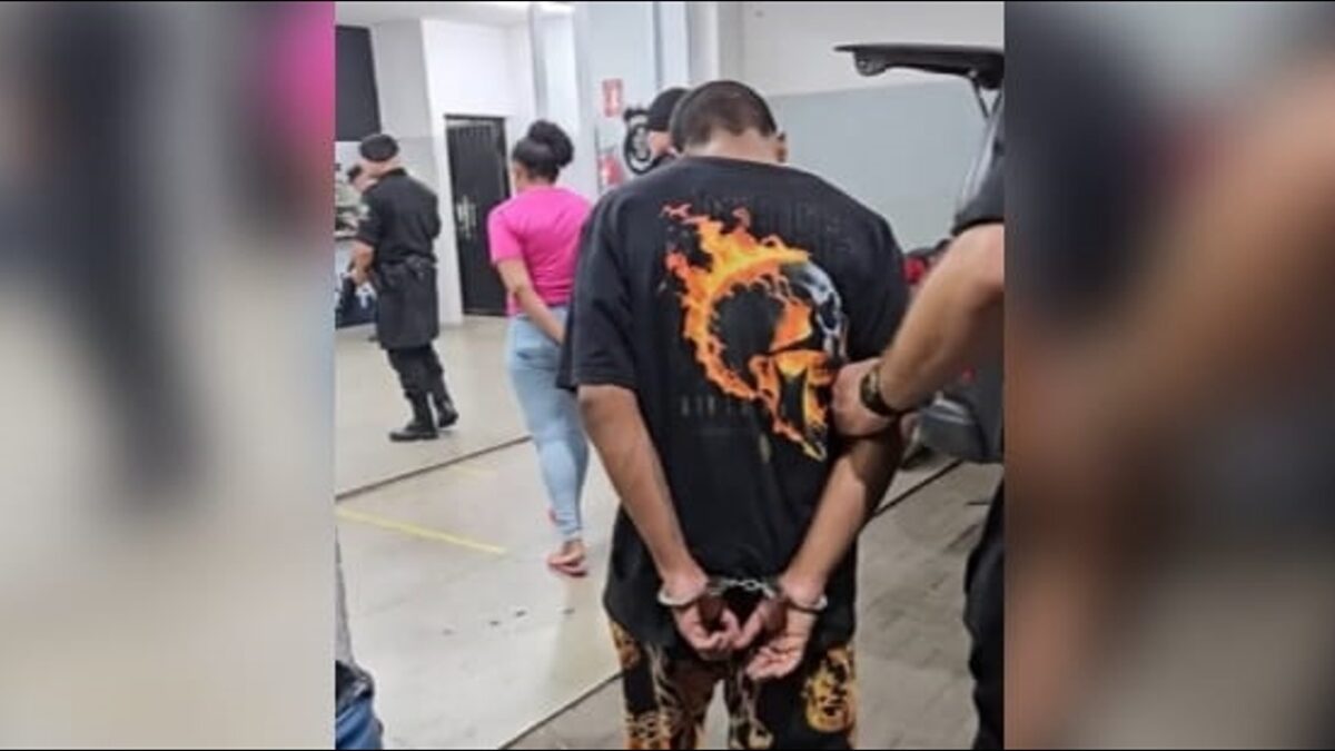 A imagem mostra o suspeito e esposa sendo levados para Central de Flagrantes