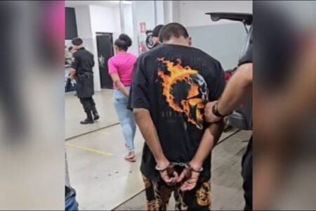 A imagem mostra o suspeito e esposa sendo levados para Central de Flagrantes