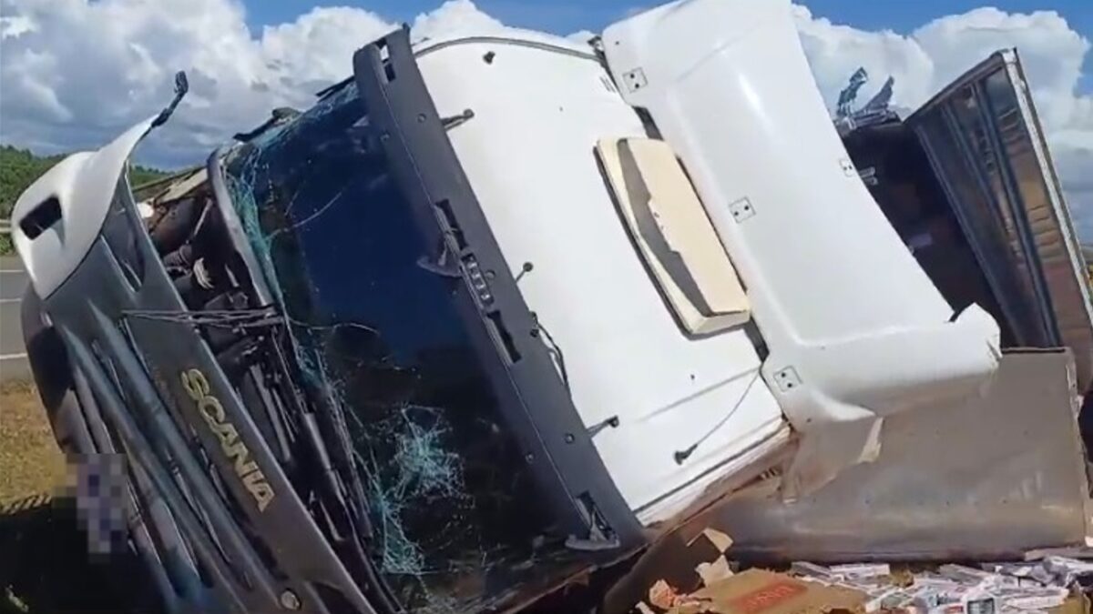 A imagem mostra um caminhão tombado, com a frente destruída após o acidente