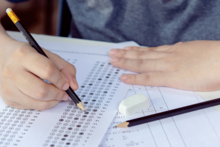 Imagem de uma pessoa preenchendo o gabarito de uma prova