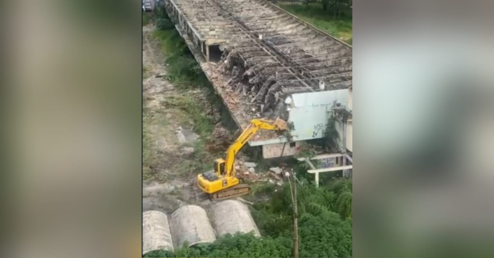 A imagem mostra uma máquina iniciando a demolição do prédio