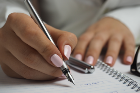 Imagem de uma mão escrevendo em um caderno