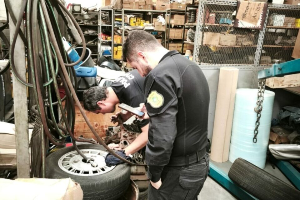 A imagem mostra policiais fazendo buscas em comércios de vendas de ferro-velho na capital