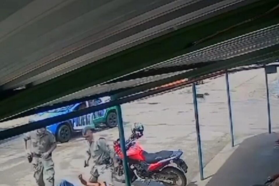 A imagem mostra um homem sendo contido por policiais militares