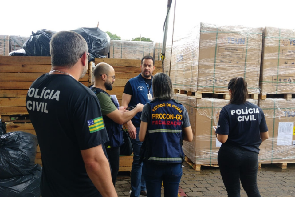 Imagem colorida mostra agentes do Procon Goiás e da Polícia Civil em uma fábrica que comercializava placas solares de forma irregular.