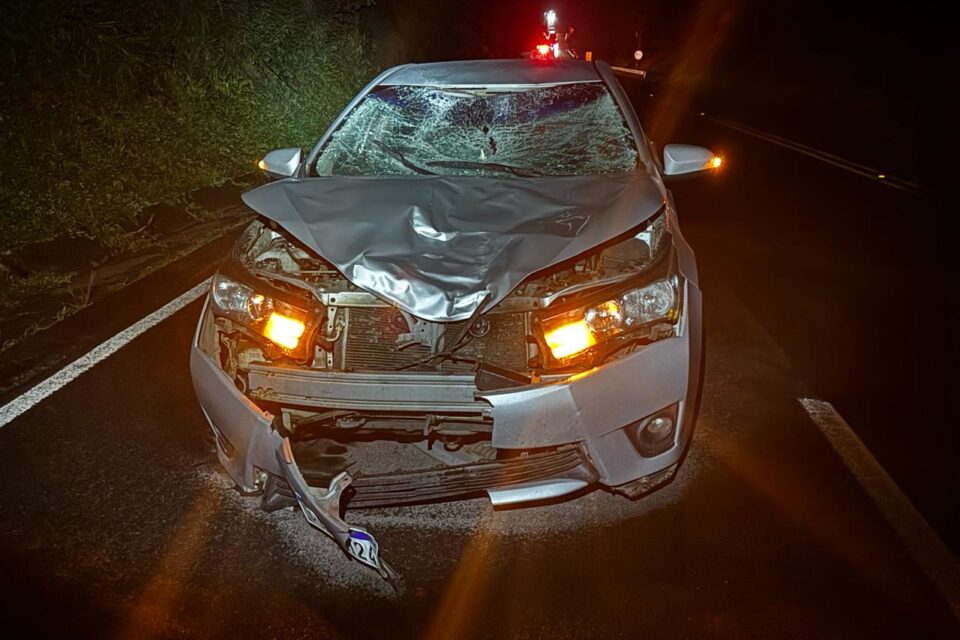 A imagem mostra um carro com a frente danificada após atropelar um pedestre