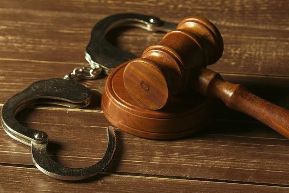A imagem mostra um martelo de tribunal e um par de algemas abertas