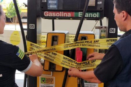 A imagem mostra fiscais interditando bombas de combustíveis