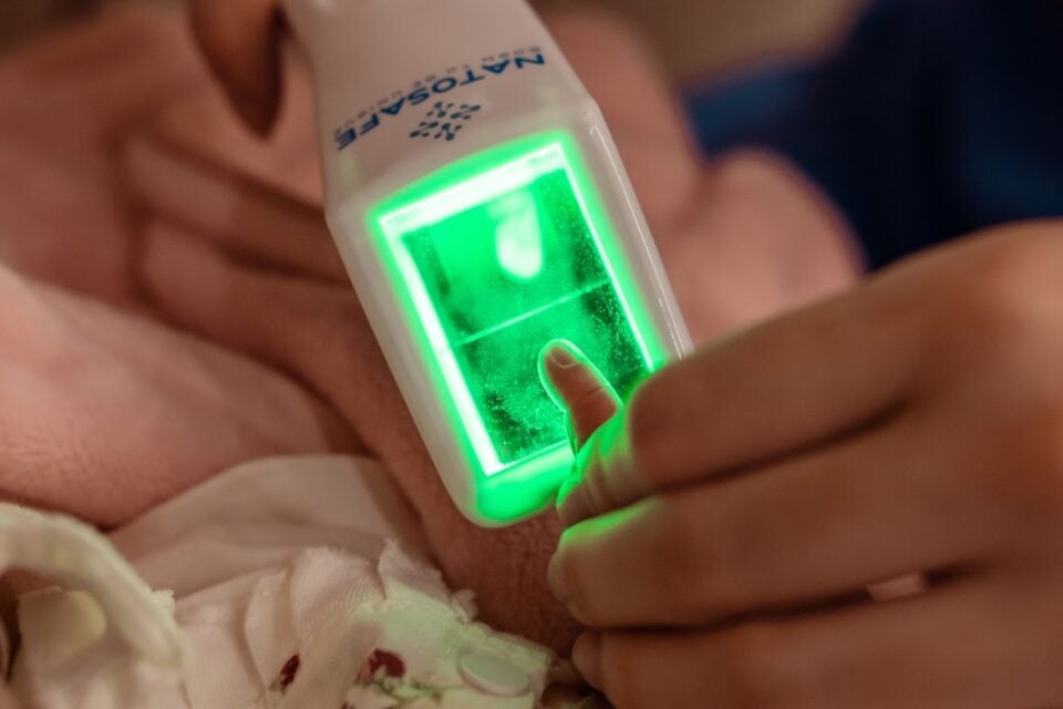 A imagem mostra a coleta de biometria de um recém-nascido