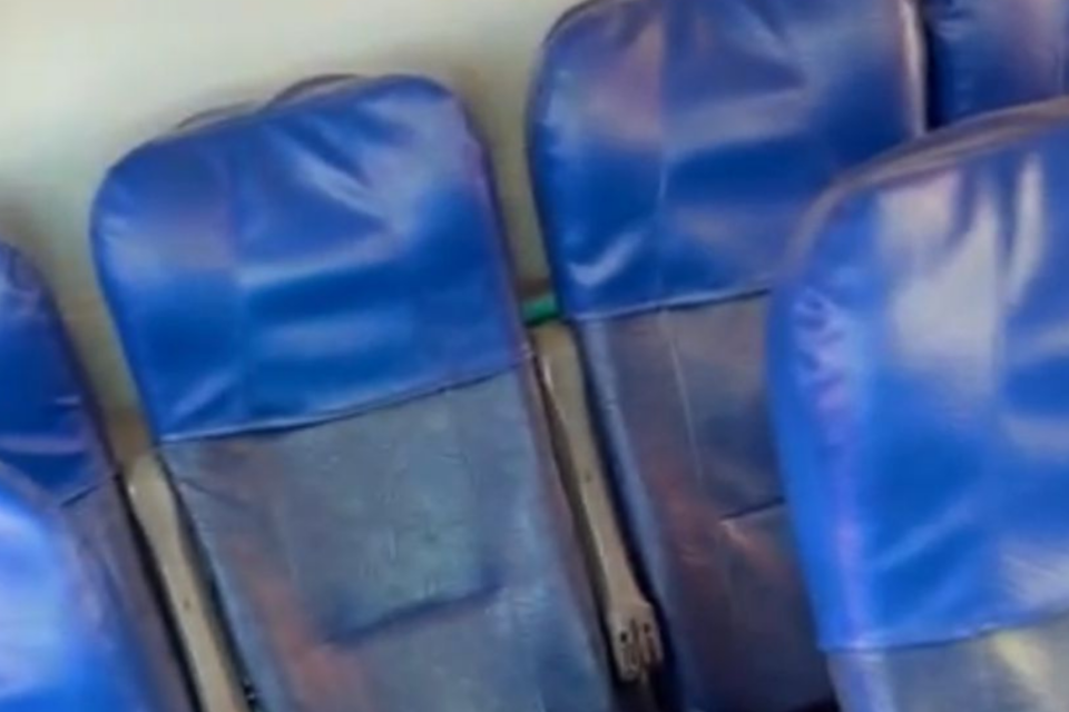 Imagem colorida mostra bancos de um ônibus escolar com capas azuis na parte de cima.