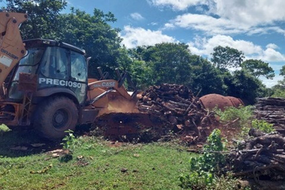 A imagem mostra um trator destruindo os fornos encontrados na operação