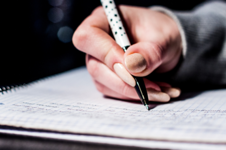 Imagem de uma mulher escrevendo no caderno