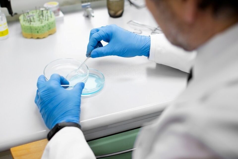 A imagem é ilustrativa de um biólogo manipulando material de pesquisa em laboratório
