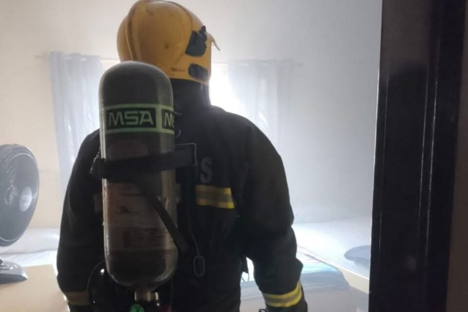 A imagem mostra um bombeiro entrando no local do incêndio