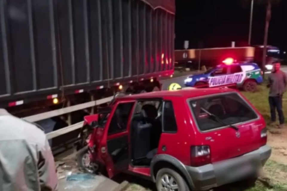 Imagem colorida mostra um carro vermelho batido ao lado de uma careta.