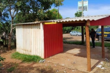 Imagem colorida mostra um quiosque, localizado às margens da rodovia em Anápolis com uma viatura da Polícia Rodoviária Federal ao fundo.