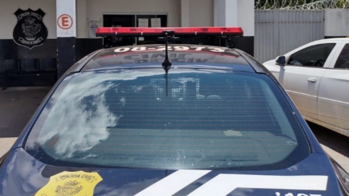 A imagem mostra uma viatura na frente da delegacia