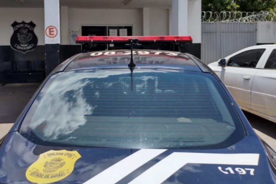 A imagem mostra uma viatura na frente da delegacia
