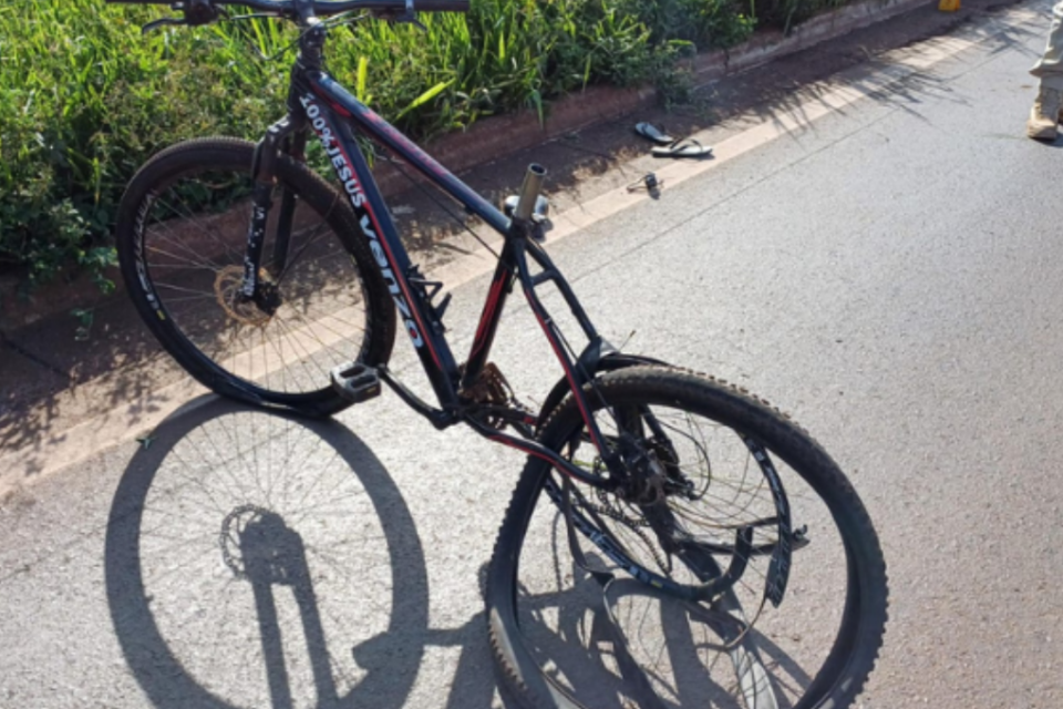 Imagem colorida mostra uma bicicleta com a roda traseira retorcida após um acidente em uma rodovia.