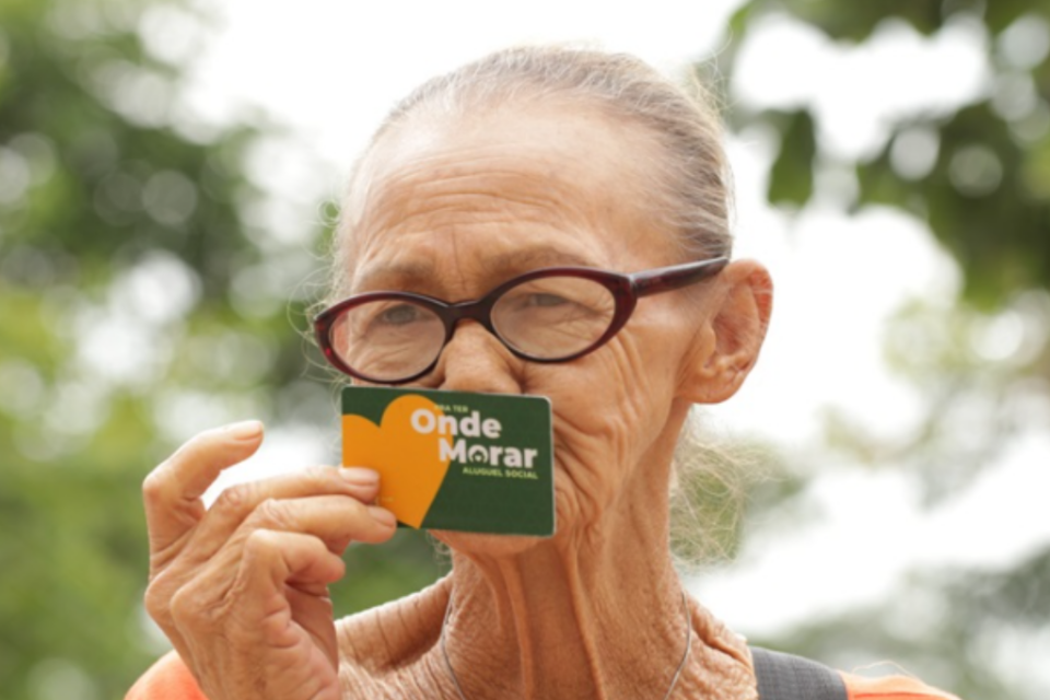 Imagem de uma pessoa idosa segurando o cartão do programa Pra Ter Onde Morar