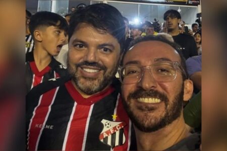 A imagem mostra o prefeito com um jornalista que atuava no esquema