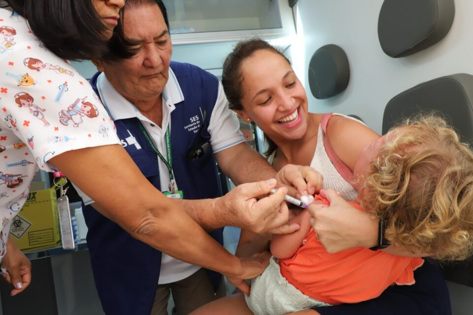 A imagem mostra uma criança sendo vacinada