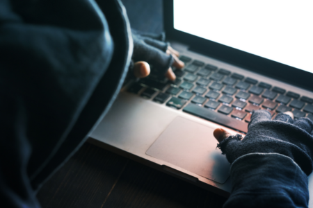 Imagem de um homem encapuzado usando o notebook