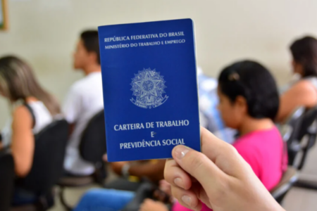 Imagem de uma mão segurando uma carteira de trabalho