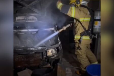A imagem mostra um bombeiro apagando o incêndio