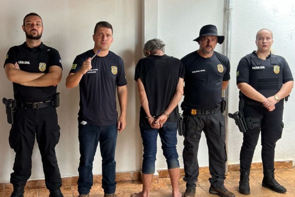 Imagem do homem preso ao lado do delegado e policiais