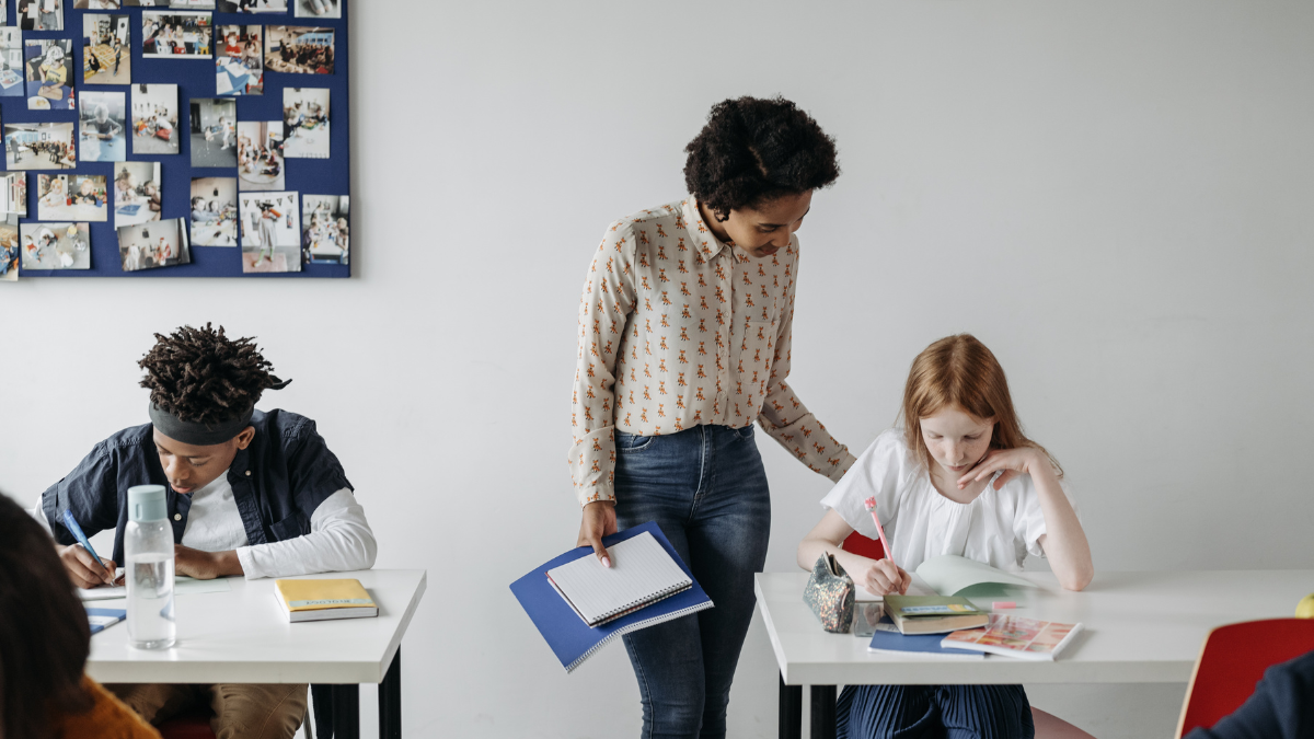 Imagem de uma mulher dando aula para alunos jovens