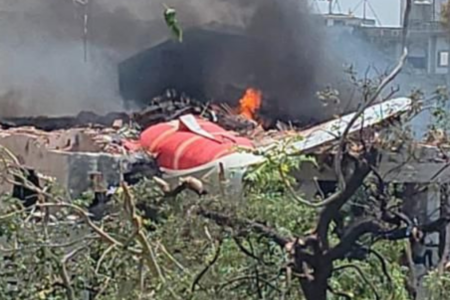 Imagem do avião caído entre as casas e árvores