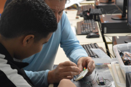 Imagem de um professor dando aula de eletrônica a um aluno