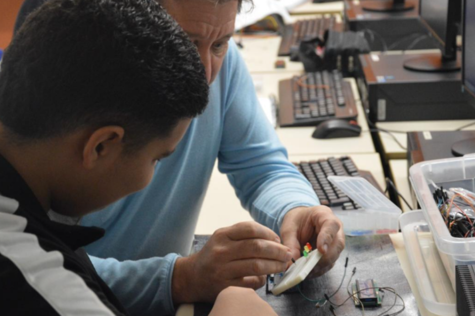 Imagem de um professor dando aula de eletrônica a um aluno