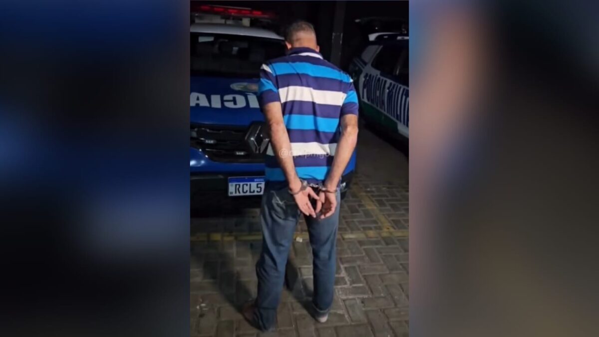 Imagem do homem preso de costas para a câmera e algemado