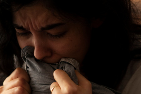 Imagem de uma mulher encolhida com medo