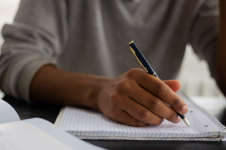 Imagem de um homem negro escrevendo em um caderno