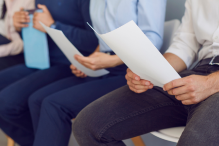 Imagem de pessoas segurando papéis para uma entrevista de emprego
