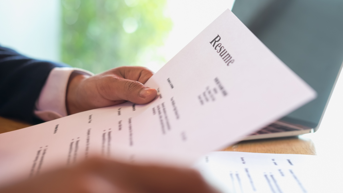 Imagem de uma pessoa segurando e lendo um currículo