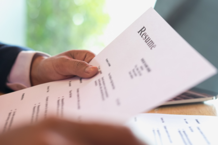 Imagem de uma pessoa segurando e lendo um currículo