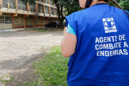Imagem de uma pessoa de costas com um uniforme de agente de combate a endemias