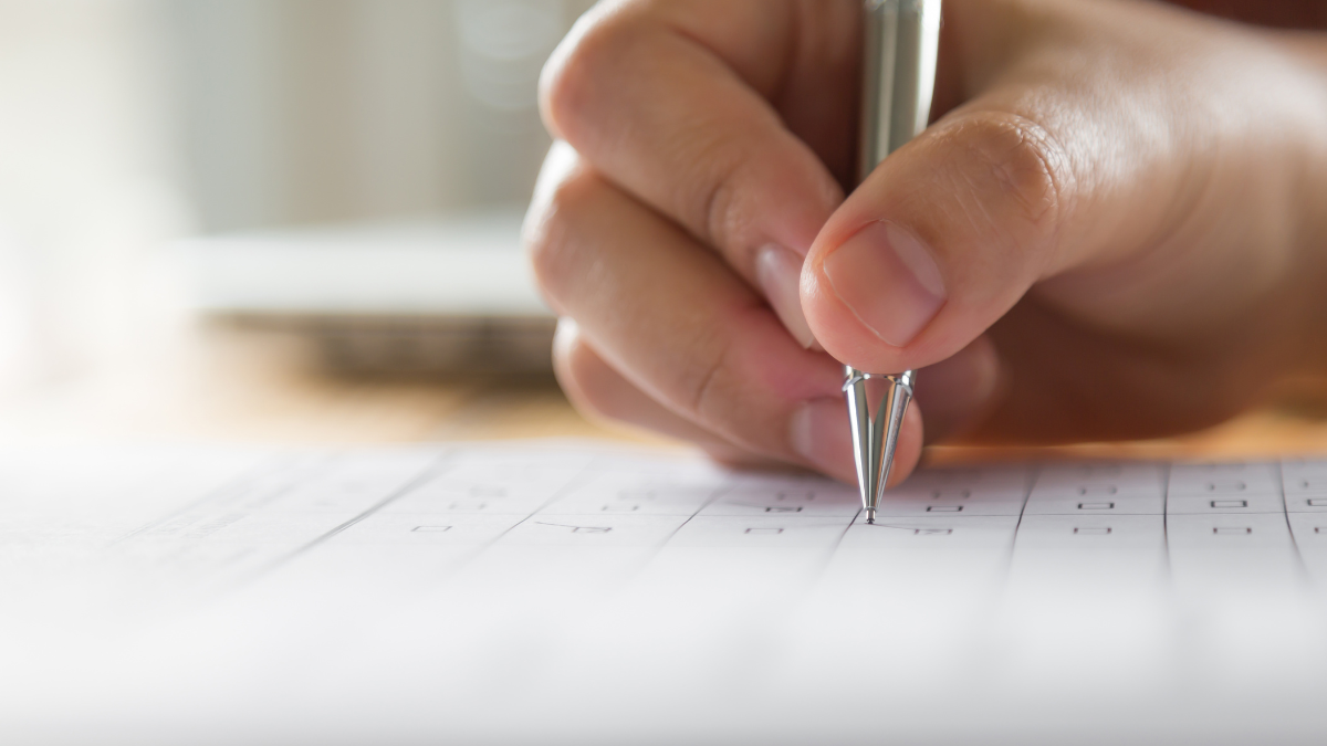 Imagem de uma mão escrevendo em uma folha de papel