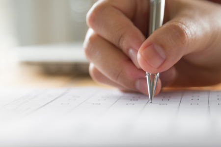 Imagem de uma mão escrevendo em uma folha de papel