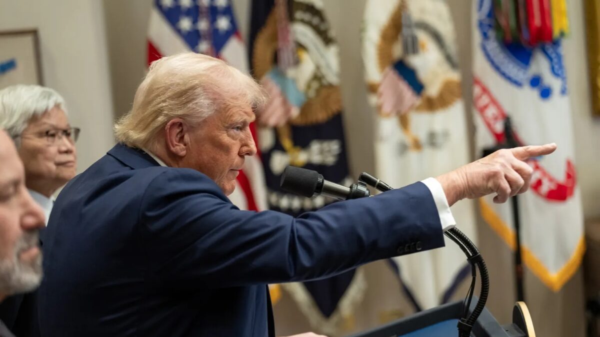 Trump aponta com o dedo com bandeira dos EUA ao fundo