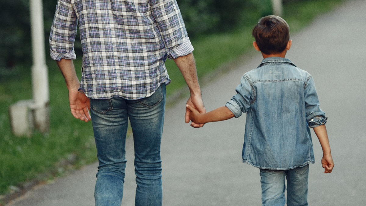 Imagem de um pai segurando a mão de uma criança