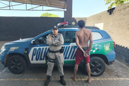Imagem do suspeito preso em frente a uma viatura